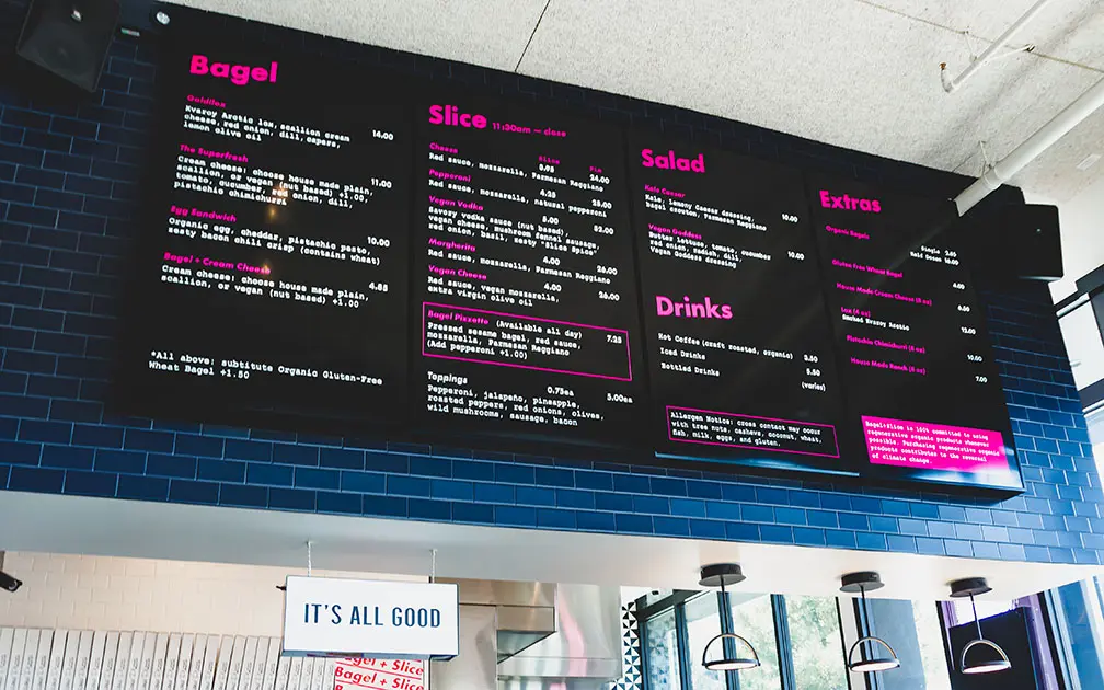 dsa-signage-bagels-and-slice-menu A menu board at a restaurant with pink lettering.