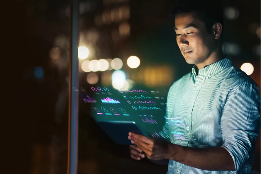 A man is looking at his tablet in the dark.