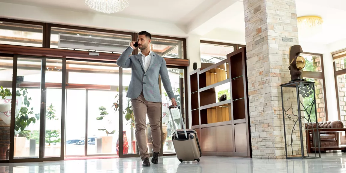 FL-WB-hospitality-featured-2880x1440 A man in suit and tie walking with luggage.