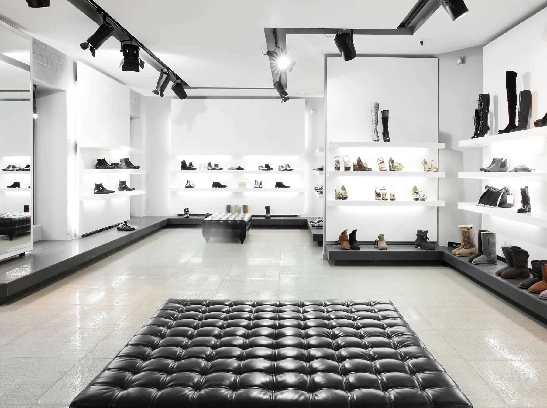 RetailSecrty A black leather ottoman in the middle of a store.